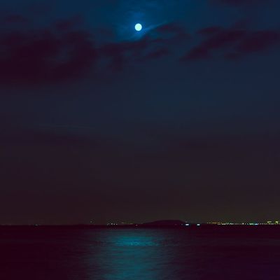 Calm water surface reflecting a dark, starry sky.